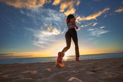 Muchacha apta que activa en una playa contra el cielo de la puesta del sol en fondo del mar imagen de archivo libre de regalías Muchacha apta que activa en una playa contra el cielo de la puesta del sol en fondo del mar imagen de archivo libre de regalías