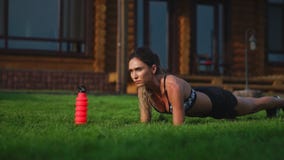 Muchacha apta que hace el ejercicio del tablón al aire libre en el día de verano caliente del parque Concepto de resistencia y de almacen de metraje de vídeo Muchacha apta que hace el ejercicio del tablón al aire libre en el día de verano caliente del parque Concepto de resistencia y de almacen de metraje de vídeo