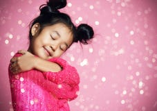 Muchacha asiática del niño con los ojos cerrados en abrazo rosado del suéter y sueño Lentejuelas de oro fotografía de archivo Muchacha asiática del niño con los ojos cerrados en abrazo rosado del suéter y sueño Lentejuelas de oro fotografía de archivo