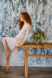 Muchacha de moda que se sienta en la tabla, pelo rojo foto de archivo Muchacha de moda que se sienta en la tabla, pelo rojo foto de archivo
