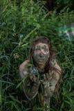 Muchacha de Muddy Amazon que oculta detrás de un arbusto en el bosque, mientras que burbujas de jabón que vuelan alrededor de ell imágenes de archivo libres de regalías Muchacha de Muddy Amazon que oculta detrás de un arbusto en el bosque, mientras que burbujas de jabón que vuelan alrededor de ell imágenes de archivo libres de regalías