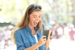 Muchacha emocionada que sostiene un teléfono elegante en la calle fotografía de archivo Muchacha emocionada que sostiene un teléfono elegante en la calle fotografía de archivo