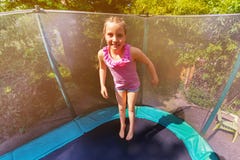 Muchacha feliz que despide para arriba en el trampolín al aire libre fotografía de archivo libre de regalías Muchacha feliz que despide para arriba en el trampolín al aire libre fotografía de archivo libre de regalías