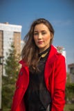 Muchacha hermosa en una capa roja en un fondo de casas fotografía de archivo libre de regalías Muchacha hermosa en una capa roja en un fondo de casas fotografía de archivo libre de regalías
