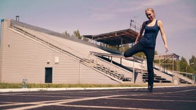 Muchacha linda joven, constitución deportiva, en el estadio Ella hace el calentamiento de los músculos, antes de entrenar metrajes Muchacha linda joven, constitución deportiva, en el estadio Ella hace el calentamiento de los músculos, antes de entrenar metrajes
