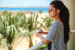 Muchacha que goza de la taza de café en un balcón imágenes de archivo libres de regalías Muchacha que goza de la taza de café en un balcón imágenes de archivo libres de regalías