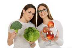 Muchacha que sostiene manzanas rojas y muchacha que lleva a cabo vegelables imagenes de archivo Muchacha que sostiene manzanas rojas y muchacha que lleva a cabo vegelables imagenes de archivo