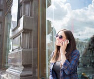 Muchacha sonriente del inconformista en ropa de sport fresca que habla en el teléfono móvil, colocándose al aire libre en la call imágenes de archivo libres de regalías Muchacha sonriente del inconformista en ropa de sport fresca que habla en el teléfono móvil, colocándose al aire libre en la call imágenes de archivo libres de regalías
