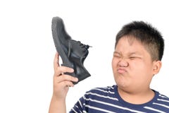 Muchacho asqueado que sostiene un par de zapatos de cuero hediondos fotos de archivo libres de regalías Muchacho asqueado que sostiene un par de zapatos de cuero hediondos fotos de archivo libres de regalías