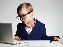 Muchacho del negocio niño divertido en vidrios que escribe la pluma pequeño jefe en oficina Foto de archivo libre de regalías Muchacho del negocio niño divertido en vidrios que escribe la pluma pequeño jefe en oficina Foto de archivo libre de regalías