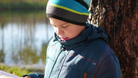 Muchacho en parque del otoño cerca del lago que lee un libro Un paisaje hermoso del otoño Educación escolar almacen de metraje de vídeo Muchacho en parque del otoño cerca del lago que lee un libro Un paisaje hermoso del otoño Educación escolar almacen de metraje de vídeo