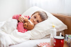 Muchacho enfermo del niño que miente en cama con una fiebre, descansando imagenes de archivo Muchacho enfermo del niño que miente en cama con una fiebre, descansando imagenes de archivo