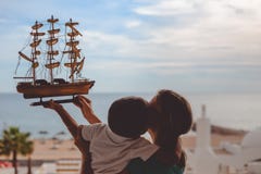 Muchacho feliz que besa a la madre y que lleva a cabo el modelo de nave encendido fotografía de archivo Muchacho feliz que besa a la madre y que lleva a cabo el modelo de nave encendido fotografía de archivo