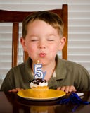 Muchacho joven que sopla hacia fuera la vela del cumpleaños foto de archivo libre de regalías Muchacho joven que sopla hacia fuera la vela del cumpleaños foto de archivo libre de regalías