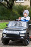 Muchacho lindo en montar un coche eléctrico negro en el parque fotografía de archivo Muchacho lindo en montar un coche eléctrico negro en el parque fotografía de archivo