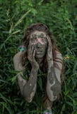 Muddy Amazon girl hiding behind a bush in the woods, while soap bubbles flying around her Royalty Free Stock Image Muddy Amazon girl hiding behind a bush in the woods, while soap bubbles flying around her Royalty Free Stock Image
