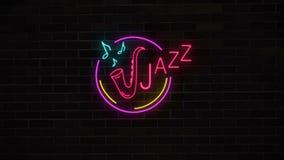 Muestra de neón del jazz con el saxofón y notas sobre la pared de ladrillo Muestra de neón del jazz con el saxofón y notas sobre la pared de ladrillo