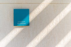 Muestra de no fumadores en la pared blanca texturizada, Abu Dhabi imágenes de archivo libres de regalías Muestra de no fumadores en la pared blanca texturizada, Abu Dhabi imágenes de archivo libres de regalías