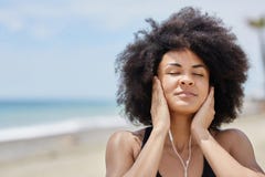 Mujer afroamericana que se relaja en música que escucha de la playa fotos de archivo libres de regalías Mujer afroamericana que se relaja en música que escucha de la playa fotos de archivo libres de regalías