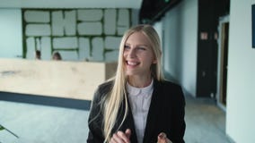 Mujer alegre en la oficina que agita con la mano Mujer joven elegante en la chaqueta que agita con la mano al saludo anónimo de l metrajes Mujer alegre en la oficina que agita con la mano Mujer joven elegante en la chaqueta que agita con la mano al saludo anónimo de l metrajes