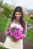 Mujer alegre linda que sostiene la flor en pote fotos de archivo Mujer alegre linda que sostiene la flor en pote fotos de archivo