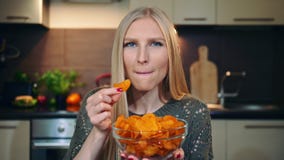 Mujer alegre que come las patatas fritas Hembra joven hermosa que goza de las patatas fritas y que mira la cámara mientras que as metrajes Mujer alegre que come las patatas fritas Hembra joven hermosa que goza de las patatas fritas y que mira la cámara mientras que as metrajes