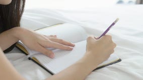 Mujer asiática del primer relajar la mentira en la cama que escribe el libro y el diario en el dormitorio en casa metrajes Mujer asiática del primer relajar la mentira en la cama que escribe el libro y el diario en el dormitorio en casa metrajes