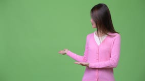Mujer asiática hermosa joven que muestra algo almacen de metraje de vídeo Mujer asiática hermosa joven que muestra algo almacen de metraje de vídeo