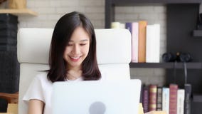 Mujer asiática independiente del retrato hermoso que trabaja el ordenador portátil en línea con sonrisa y la sentada feliz en el Mujer asiática independiente del retrato hermoso que trabaja el ordenador portátil en línea con sonrisa y la sentada feliz en el