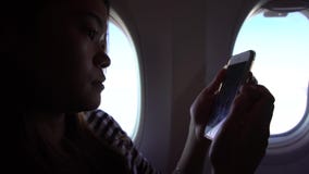 mujer asiática 4k que sostiene el smartphone con las manos durante el vuelo metrajes mujer asiática 4k que sostiene el smartphone con las manos durante el vuelo metrajes