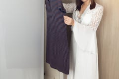 Mujer asiática que elige la ropa en guardarropa fotografía de archivo Mujer asiática que elige la ropa en guardarropa fotografía de archivo
