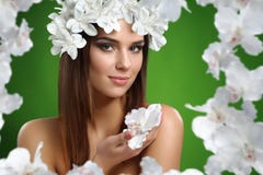 Mujer atractiva joven con las flores en su pelo que presenta en estudio imagen de archivo Mujer atractiva joven con las flores en su pelo que presenta en estudio imagen de archivo