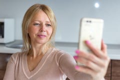 Mujer de la Edad Media que toma un selfie en casa fotografía de archivo libre de regalías Mujer de la Edad Media que toma un selfie en casa fotografía de archivo libre de regalías