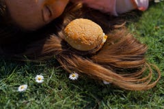 Mujer de negocios acertada que miente en la hierba con el cheesburger de la hamburguesa de los alimentos de preparaci?n r?pida en imagen de archivo Mujer de negocios acertada que miente en la hierba con el cheesburger de la hamburguesa de los alimentos de preparaci?n r?pida en imagen de archivo