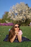 Mujer de negocios acertada que miente en la hierba que disfruta de tiempo libre del ocio en un parque con los cerezos floreciente fotografía de archivo libre de regalías Mujer de negocios acertada que miente en la hierba que disfruta de tiempo libre del ocio en un parque con los cerezos floreciente fotografía de archivo libre de regalías