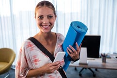 Mujer de negocios casual que sostiene la estera de la yoga imagen de archivo libre de regalías Mujer de negocios casual que sostiene la estera de la yoga imagen de archivo libre de regalías