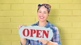 Mujer de negocios feliz del inconformista que lleva a cabo una muestra abierta fotos de archivo libres de regalías Mujer de negocios feliz del inconformista que lleva a cabo una muestra abierta fotos de archivo libres de regalías