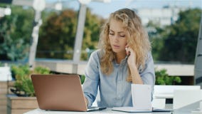 Mujer de negocios ocupada misma Trabaja con un ordenador portátil: el teléfono, mirando la grabación en un cuaderno almacen de metraje de vídeo Mujer de negocios ocupada misma Trabaja con un ordenador portátil: el teléfono, mirando la grabación en un cuaderno almacen de metraje de vídeo