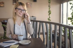 Mujer de negocios que habla en el smartphone y tomar notas, en una cafetería, restaurante foto de archivo Mujer de negocios que habla en el smartphone y tomar notas, en una cafetería, restaurante foto de archivo