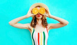 Mujer del retrato del verano que sostiene en sus manos dos rebanadas de fruta anaranjada que ocultan sus ojos en sombrero de paja fotos de archivo libres de regalías Mujer del retrato del verano que sostiene en sus manos dos rebanadas de fruta anaranjada que ocultan sus ojos en sombrero de paja fotos de archivo libres de regalías