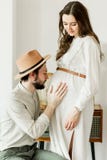 Mujer embarazada hermosa joven y su marido en la situación del sombrero cerca de la pared del cactus fotografía de archivo Mujer embarazada hermosa joven y su marido en la situación del sombrero cerca de la pared del cactus fotografía de archivo