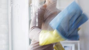 Mujer en los guantes que limpian la ventana con el trapo Mujer en los guantes que limpian la ventana con el trapo