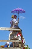 Mujer en traje púrpura y blanco con la verja que hace una pausa del parasol de encaje púrpura contra mismo el cielo del bue en el fotos de archivo Mujer en traje púrpura y blanco con la verja que hace una pausa del parasol de encaje púrpura contra mismo el cielo del bue en el fotos de archivo