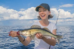 Mujer feliz del pescador con el trofeo de los pescados del zander en el barco foto de archivo Mujer feliz del pescador con el trofeo de los pescados del zander en el barco foto de archivo