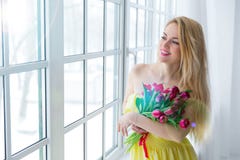 Mujer feliz joven que sonríe con el manojo del tulipán en vestido amarillo 8 de marzo día para mujer internacional imagenes de archivo Mujer feliz joven que sonríe con el manojo del tulipán en vestido amarillo 8 de marzo día para mujer internacional imagenes de archivo