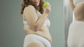 Mujer Gorda En Ropa Interior Que Admira Su Cuerpo En Espejo Y Que Come La  Manzana Verde Metrajes - Vídeo de confianza, pérdida: 115013622