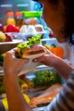 Mujer hambrienta que sostiene un bocadillo en sus manos y situación t siguiente imagen de archivo libre de regalías Mujer hambrienta que sostiene un bocadillo en sus manos y situación t siguiente imagen de archivo libre de regalías