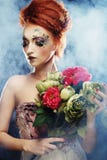Mujer hermosa del redhair que sostiene las flores imágenes de archivo libres de regalías Mujer hermosa del redhair que sostiene las flores imágenes de archivo libres de regalías