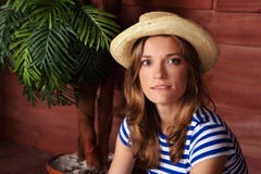 Mujer hermosa en una camisa rayada y un sombrero que se sientan en la Vera fotos de archivo Mujer hermosa en una camisa rayada y un sombrero que se sientan en la Vera fotos de archivo