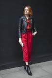 Mujer hermosa y elegante en pantalones rojos y la capa negra del leasher que presentan durante la semana de la moda de Londres Eu Imagenes de archivo Mujer hermosa y elegante en pantalones rojos y la capa negra del leasher que presentan durante la semana de la moda de Londres Eu Imagenes de archivo